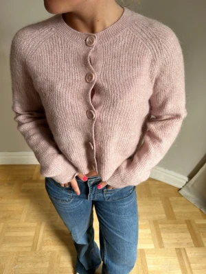 Ljusrosa stickad kofta med knappar💖 - Supermjuk ljusrosa stickad kofta med rund halsringning och fyra stora matchande knappar framtill. Koftan har lång ärm och en avslappnad passform, perfekt att slänga på sig över en t-shirt. Materialet ser ut att vara en fluffig ull- eller mohairblandning.