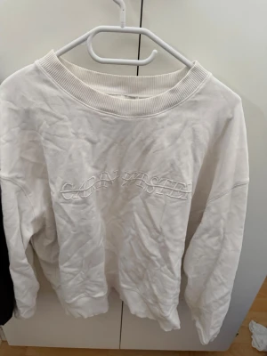 Vit sweatshirt från Carin Wester - Vit sweatshirt från Carin Wester med broderad logga framtill. Tröjan har rund halsringning med bred ribbad kant och långa ärmar. Perfekt för en avslappnad och stilren look.