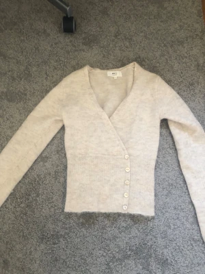 Beige kofta från Gina Tricot XS - Mysig beige kofta från Gina Tricot i alpackablandning. Koftan har v-ringning, långa ärmar och knäppning med fem knappar framtill. Perfekt för lager-på-lager och en stilren look. Pris kan diskuteras💕💕