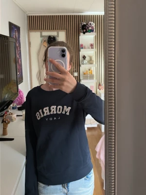 Svart sweatshirt Morris Lady - Säljer en mörkblå sweatshirt från Morris Lady med tryckt logga framtill i vitt och beige. Tröjan har rund halsringning, långa ärmar och ribbade muddar vid ärmslut och nederkant. Perfekt till jeans eller mjukisbyxor för en chill look. Som ni ser på bilden har den fått lite färg på sig men inget som syns om man inte kollar nära🤗