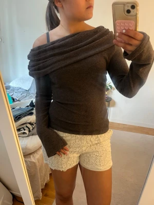 Brun off shoulder tröja - Snygg brun off shoulder tröja med draperad krage och långa ärmar. Tröjan är figurnära. Materialet känns mjukt och stretchigt. Den är endast använd 1 gång