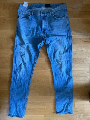 Ljusblå slim fit jeans - Säljer ett par ljusblå slim fit jeans med klassisk femficksdesign och normal midja. Jeansen har dragkedjegylf och raka ben. Perfekta till en avslappnad och trendig look. Materialet är mjuk denim i bomull.