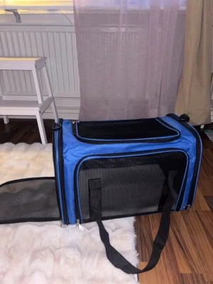 HELT NY transportväska för husdjur - Praktisk blå transportväska för husdjur, köpte fel storlek så den är helt ny, endast nosad på😄Köpt på Amazon för 425kr. Väskan har dragkedjor, går att öppna fram, ovanifrån och från sidan, samt en mjuk vit dyna inuti. Perfekt för att ta med ditt husdjur på resor eller till veterinären. Kommer med ett längre axelband också. Lx50,Bx34,Hx34.