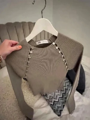 Beige stickad tröja från Zara - Trendig beige stickad tröja från Zara med långa ärmar och coola dekorativa knappar längs axlarna. Tröjan har rund halsringning och är ribbstickad för en snygg passform. 