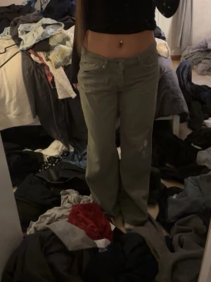 Grön loose fit jeans - Säljer ett par gröna loose fit jeans med raka ben och låg midja. Jeansen har klassisk femficksdesign och stängs med knapp och dragkedja. Perfekta för en avslappnad och trendig look.