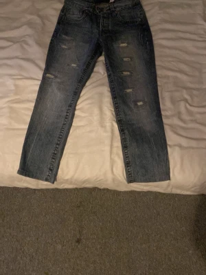 Blå slitna raka jeans dolce gabbana - Säljer ett par blå jeans med rak passform och slitna detaljer framtill. Jeansen har klassisk femficksdesign och är gjorda i denim. Perfekta för dig som gillar en avslappnad och trendig stil.