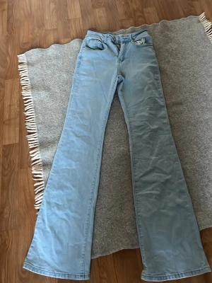 Ljusblå utsvängda jeans - Säljer ett par ljusblå jeans med utsvängda ben och klassisk femficksdesign. Jeansen har hög midja och bälteshällor. Perfekta för dig som gillar jeans 