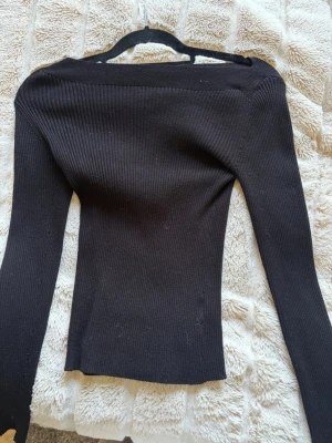 Svart ribbad topp från Kappahl - Säljer en svart, ribbad långärmad topp från Kappahl i storlek XS. Toppen har en tight passform och är tillverkad i ett stretchigt material som sitter snyggt på kroppen. Perfekt att styla med jeans eller kjol för en clean look.