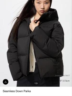 Uniqlo Svart pufferjacka Seamless Down Parka - Säljer en svart pufferjacka från Uniqlo, modell Seamless Down Parka. Jackan har hög krage, diskret dragkedja och en stilren, passform. Tillverkad i ett slätt material med dunfyllning som håller dig varm under kalla dagar. Perfekt för dig som vill ha en clean och modern vinterlook. Den är i väldigt bra skick och nypris är: ca 1700