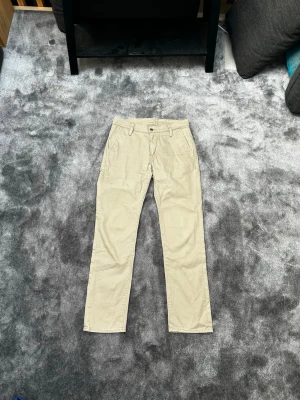 Beiga raka jeans från Levis  - Snygga beiga jeans med rak passform och klassisk design. Byxorna har framfickor, hällor för bälte och två bakfickor. Perfekta för en clean och stilren look. Materialet känns mjukt och bekvämt, passar till många olika outfits. Storlek 32/32