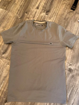 Grå Lacoste  - Fin Lacoste passar bra till s och lite mer åt tajtare sidan för storlek M. Sitter jätte fint!