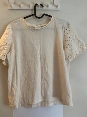 Vit blus med broderade ärmar Kappahl - Superfin vit blus från Kappahl med korta ärmar i broderad spets. Toppen har rund halsringning och är gjord i mjuk bomull. Perfekt för en fräsch och stilren look.