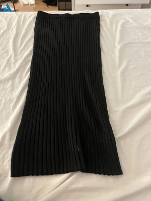 Svart ribbad långkjol från Lindex - Säljer en svart ribbad långkjol från Lindex i storlek XS. Kjolen har en rak passform och är tillverkad i ett stretchigt material som sitter snyggt på kroppen. Perfekt att styla med en enkel topp eller stickad tröja.
