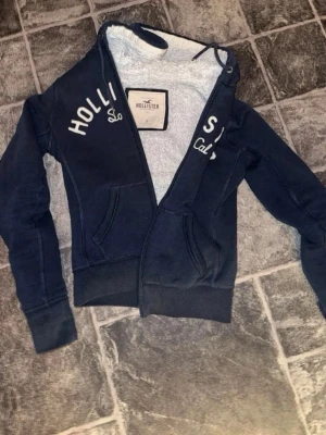 Hollister Hoodie - Säljer en marinblå hollister hoodie, storleken är S men passar bättre för xs och tröjan är i väldigt fint skick. Pris kan diskuteras vid snabb affär.