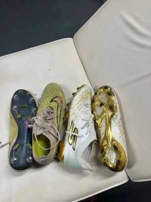 Nike och sketchers  - Två par fotbollsskor, ett par Nike i gulgrönt med svart och rosa swoosh, och ett par sketchers i vitt med gulddetaljer och svart logga.  Phantom lite använda med nya skruvdubb. 1800 kr för dem. Sketchers hela oanvända 1100 för dem .  2500 för båda. Hör av er vid bud 
