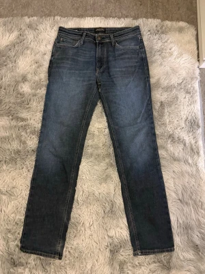 Mörkblå regular jeans - Säljer ett par mörkblå jeans med rak passform och klassisk femficksdesign. Jeansen har subtila slitningar och kontrastsömmar. Perfekta till en avslappnad stil och passar till det mesta. Materialet är troligtvis bomull med lite stretch.