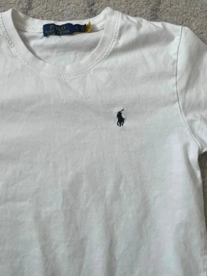 Vit t-shirt från Polo Ralph Lauren - Klassisk vit t-shirt från Polo Ralph Lauren med rund halsringning och den ikoniska broderade loggan på bröstet. Tillverkad i mjuk bomull som känns skön mot huden. Perfekt basplagg för en clean och stilren look. I fint skick. Skriv om frågor💕💕