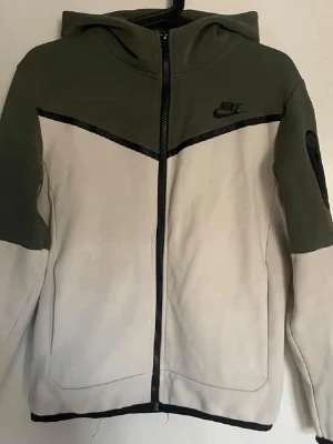 Nike tech dress - Säljer en snygg mjukisdress från Nike i olivgrönt och beige med svart Nike-logga. Jävligt skönt och riktigt snyggt, hör av er vid fler bilder. Svarar alltid så snabbt jag kan 😊 pris är såklart inte hugget i sten (byten går absolut)