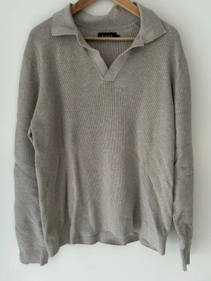 Beige stickad tröja med krage från Brothers - Snygg beige stickad tröja från Brothers (Riley) med klassisk krage och v-ringning. Tröjan har långa ärmar och är ribbstickad för en stilren look. Perfekt för lager på lager och enkel att matcha med olika outfits. Köpte tröjan för 400kr och säljer den för 200kr då den nästan är oanvänd. 