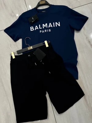 Balmain Paris blått set - Snyggt set från Balmain Paris med en marinblå t-shirt i bomull och matchande svarta shorts. 
