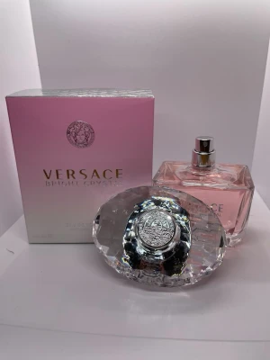Versace Bright Crystal Eau de Toilette - Versace Bright Crystal är en lyxig parfym med en elegant, fyrkantig glasflaska fylld med ljusrosa doft. Flaskan har ett stort, kristalliknande lock och kommer i en snygg rosa och vit förpackning med Versace-loggan i silver. Perfekt för dig som gillar exklusiva och fräscha dofter.