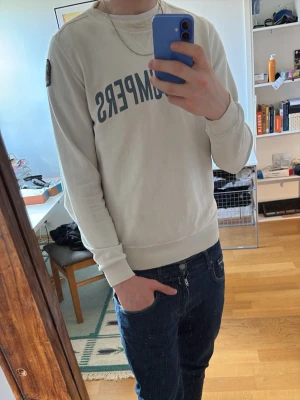 Vit sweatshirt från Parajumpers - Säljer en stilren vit sweatshirt från Parajumpers. Tröjan har rund halsringning, ribbade muddar vid ärmslut och nederkant samt en avslappnad passform. Perfekt till jeans eller andra byxor för en enkel och snygg look.