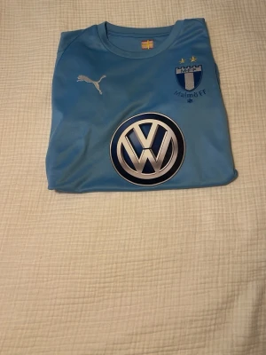 Ljusblå Malmö FF matchtröja Puma - Ljusblå Malmö FF matchtröja från Puma med klubbmärke, två stjärnor, och stora Volkswagen- och TicTac Interactive-loggor. Tillverkad i funktionsmaterial som andas, perfekt för fotbollsträning eller att bära på läktaren.