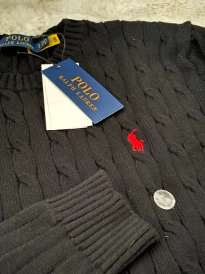 Ralph Lauren svart stickad tröja – storlek S – stickat - Svart stickad tröja från Ralph Lauren. Märke: Ralph Lauren Skick: Utmärkt skick Färg: Svart Längd: ca 63 cm Storlek: S Stil: Klassisk stickad tröja Ren och tidlös design som är lätt att styla för både vardagliga och eleganta outfits. Högkvalitativ stickning och mycket bekväm att bära. 100 % äkta Ralph Lauren-plagg. Snabb leverans. Tveka inte att kontakta mig om du har några frågor.