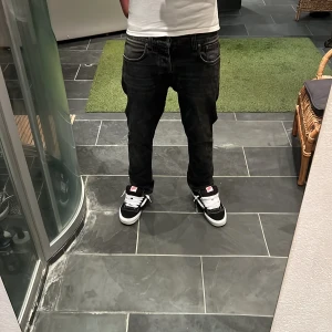 Black Nudie Jeans - Längd = 91cm                                                          Midja = 40cm.                                                         Säljer ett par svarta jeans från Nudie Jeans med klassisk femficksdesign och diskret logga på bakfickan. Jeansen har en rak passform och är tillverkade i mjukt denimtyg. Snyggt slitna detaljer och mörk tvätt ger en cool look.