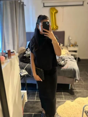 Svart långklänning med hög hals - Stilren svart tröja med hög hals och ärmlös design. Kjolen har en rak passform och är enkel men elegant, perfekt för dig som gillar minimalistisk stil. Matchas snyggt med accessoarer för en personlig touch./// använt 2 gånger 