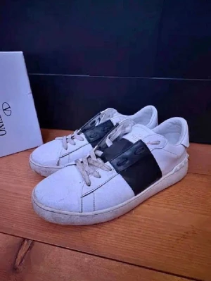 Valentino Open Garavani - Snygga vita sneakers från Valentino Garavani med en bred svart läderdetalj över snörningen och ikoniska nitar runt hälen. Skorna är i hyfsat bra skick och kan tvättas innan postning, storlek 42-43.