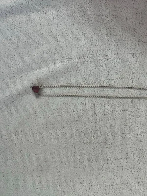 Halsband med röd hjärtformad sten - Snyggt halsband med en tunn silverfärgad kedja och ett hjärtformat rött hänge i glas eller kristall. Perfekt för dig som vill ha en enkel men ändå iögonfallande detalj till din outfit. Hjärtat har en glansig finish och kedjan är diskret.