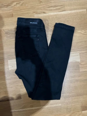 Svarta  jeans från Replay - Säljer ett par svarta jeans från Replay med klassisk femficksdesign och dragkedjedetalj på bakfickan. Jeansen har en smal passform och är tillverkade i ett stretchigt material för extra komfort. Perfekta till alla typer av outfits.