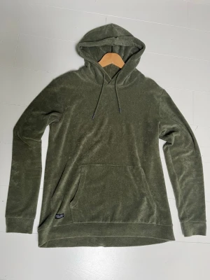 Olivgrön velourtröja Robbie Moor - Mjuk och skön olivgrön tröja i velour från Robbie Moor. Tröjan har lång ärm, rund hals och en avslappnad passform. Perfekt för dig som gillar en chill och stilren look.