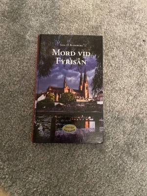 Mord vid Fyrisån & Livet efter dig - Två skönlitterära böcker: 'Mord vid Fyrisån' av Stig O. Blomberg, en svensk deckare med mörk omslagsbild av Uppsala domkyrka, och 'Livet efter dig' av Jojo Moyes, en romantisk roman med ett omslag i varma färger och motiv av två personer. Perfekt för dig som gillar spänning och kärlek.