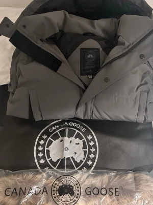 Grå Canada Goose Wyndham  - Grå Canada Goose Wyndham med svart badge med påse och päls som ingår.