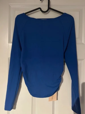 Topp med öppen rygg  - Säljer en blå långärmad topp med tight passform och rund halsringning. Toppen har en öppen rygg som ger en snygg och feminin touch samtidigt som designen framtill är enkel och stilren. Supersnygg att matcha med höga jeans eller kjol. (Ifrån Shein) 