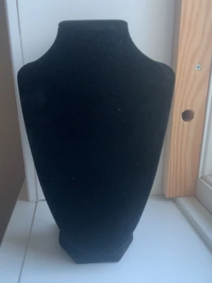 Svart smycker hållare till halsband  - En snygg smycker hållare, perfekt för att visa upp halsband eller kedjor. Formen är klassisk och elegant, vilket gör den enkel att använda både hemma och i butik. Materialet ger en lyxig känsla och framhäver smycken på ett snyggt sätt, fint och ha på sminkbordet.