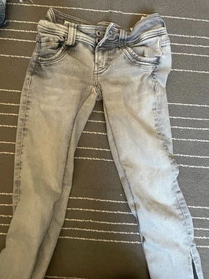 Ljusgrå lågmidjade jeans  - Säljer ett par ljusgrå jeans med fem fickor och snygga sömmar på bakfickorna. Jeansen har låg midja och klassisk dragkedja med knapp. Perfekta till en avslappnad streetstyle-look. Jeansen är i väldigt bra skick då jag inte alls använt de särskilt mycket! Pris kan diskuteras. De är köpta för 700kr  