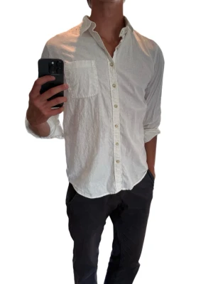 Vit tjock linneskjorta från Dressmann - Klassisk vit skjorta från Dressmann i linne med lång ärm och bröstficka. Skjortan har knappar hela vägen framtill och en avslappnad passform. Perfekt till både jeans och chinos för en clean och enkel stil.