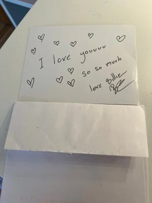 Billie eilish autograf och bild + brev - Unikt handskrivet brev dekorerat med hjärtan, svartvitt foto och tillhörande vitt kuvert med frimärke och adressetikett. Perfekt som samlarobjekt eller personlig present. Brevet är skrivet med svart bläck på vitt papper av Billie eilish.