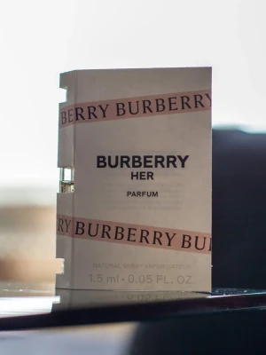 Burberry Her Parfum provflaska - Burberry Her Parfum i en liten provflaska på 1,5 ml. Doften har inslag av körsbär, amber och vanilj för en söt och sofistikerad känsla. Förpackningen är vit med rosa Burberry-band och innehåller en miniatyrflaska med sprayfunktion.