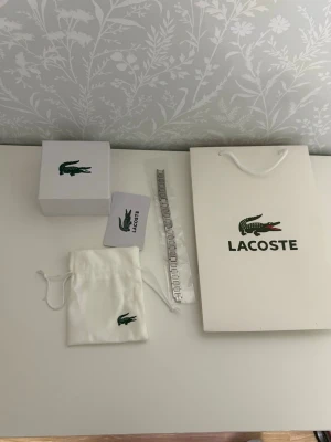 Lacoste - Helt ny o fint att ha på sig den eller ge den som present.                                                                             Med bra pris!!!                                     .               .           !!! Har flera om ni vill köpa mer än en o angår samma som bilden kommer med box o påse, priset kan diskuteras!!!