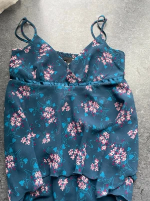 Blommig blå linnetopp med smala band - Supersöt blå linnetopp med rosa och vita blommor. I storlek 34/XS☺️ Skriv för frågor eller fler bilder! 