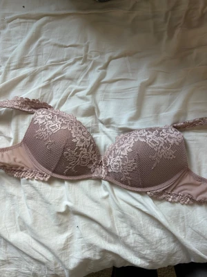 Intimissimi bh med blommönster - Säljer en snygg bh i ljusrosa nyans med vacker spets och blommönster. Bh:n har vadderade kupor och breda spetsband som ger extra stöd och en feminin look. Materialet är mjukt och behagligt, perfekt för dig som vill ha något både stilrent och romantiskt.