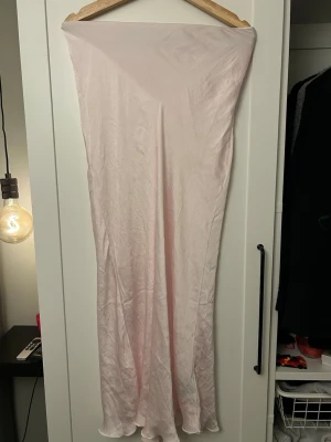 Ljusrosa långklänning  - Säljer en elegant ljusrosa lång kjol, med dragkedja i sidan och resår i midjan.
