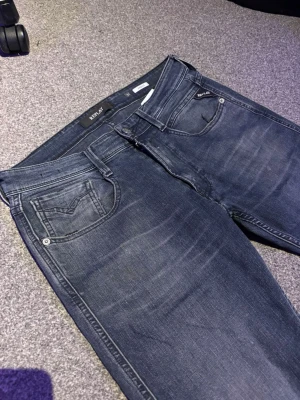 Mörkblå jeans från Replay - Snygga mörkblå skinny jeans från Replay med klassisk femficksdesign och diskreta slitningar framtill. Jeansen har låg midja och smal passform som sitter tajt längs benen. Perfekta för en trendig och avslappnad look.