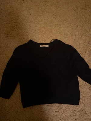 Svart cardigan från ZARA - Stilren svart cardigan från ZARA med knappar framtill och rund halsringning. Tröjan har långa ärmar och en rak passform, perfekt att slänga över en topp. Materialet känns mjukt och lätt, vilket gör den enkel att bära till olika outfits.