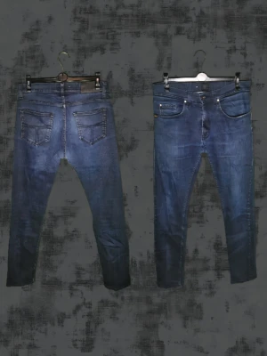 Mörkblå slim fit jeans - Säljer ett par mörkblå slim fit jeans med klassisk femficksdesign och smal passform. Jeansen har en snygg tvättad look och detaljerade sömmar. Perfekta för en trendig och avslappnad stil.