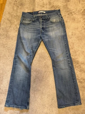 Levis 512 Bootcut - Säljer detta sällsynta par vintage Levis 512 Bootcut som är en av de mest eftertraktade jeansen just nu. Storleken är 32/32. Fin tvättad färg med många fades och gula kontrastsömmar. De har distressing vid ena framfickan och vid hälarna men inga hål förekommer. Midjan är 42,5 cm och ytterbenslängden är 104 cm. Hör gärna av dig vid frågor eller prisförslag!